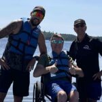 Un participant de planche à pagaie adapté et 2 accompagnateurs